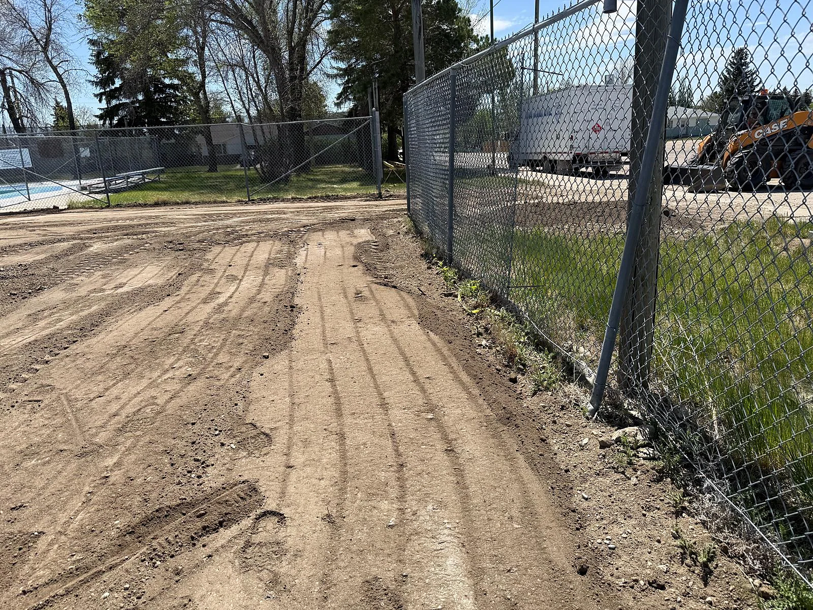 Ground-level preparation along a chain-link fence