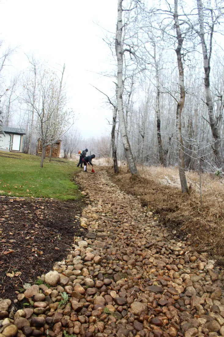 After cleanup, exposed rock-lined channel beside an acreage lawn