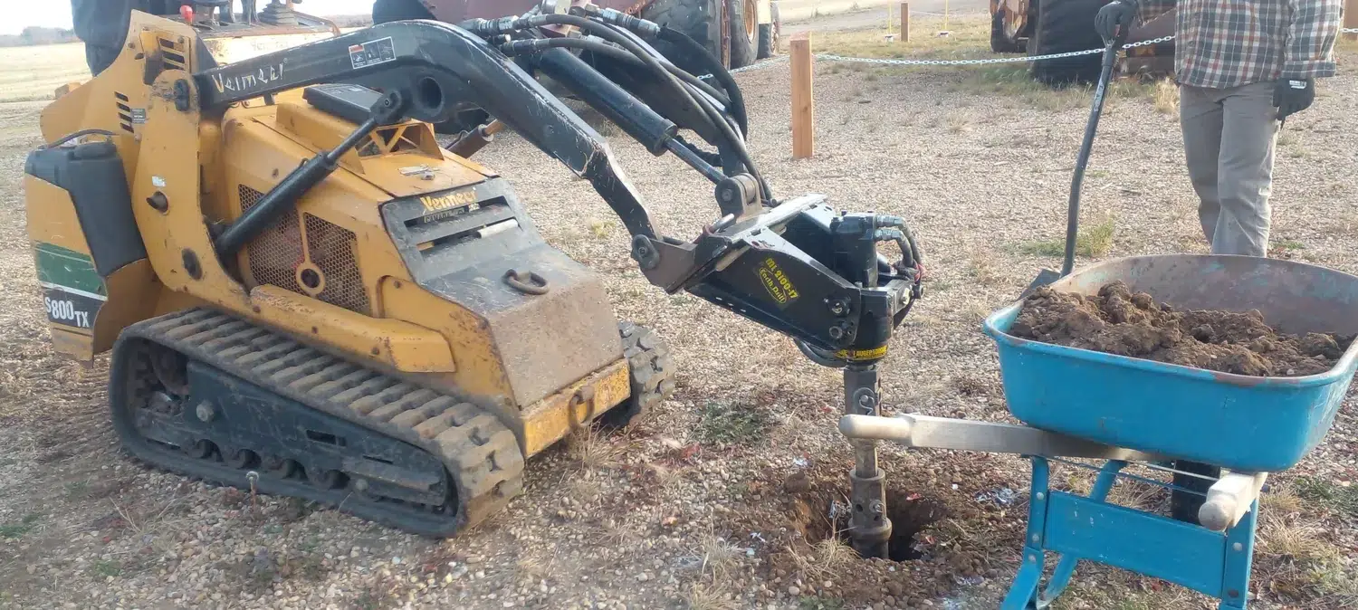 Compact tracked loader with auger at an outdoor site
