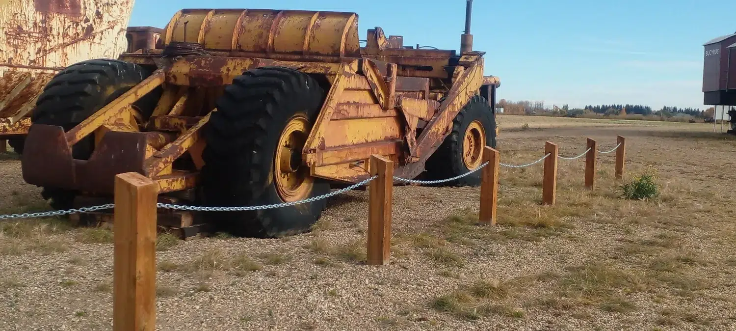 Timber post-and-chain barrier beside large equipment