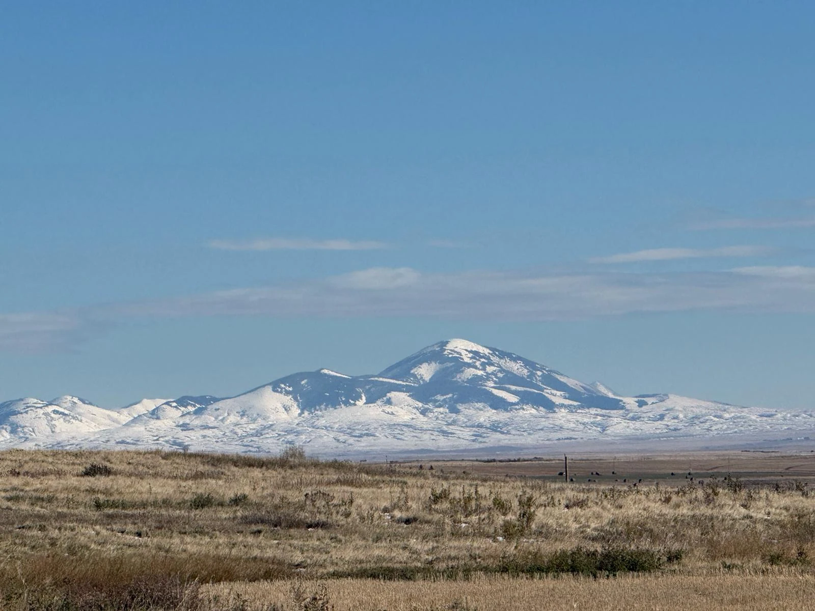 Original photograph of snow-capped mountains rising beyond the Southern Alberta prairie under a blue sky